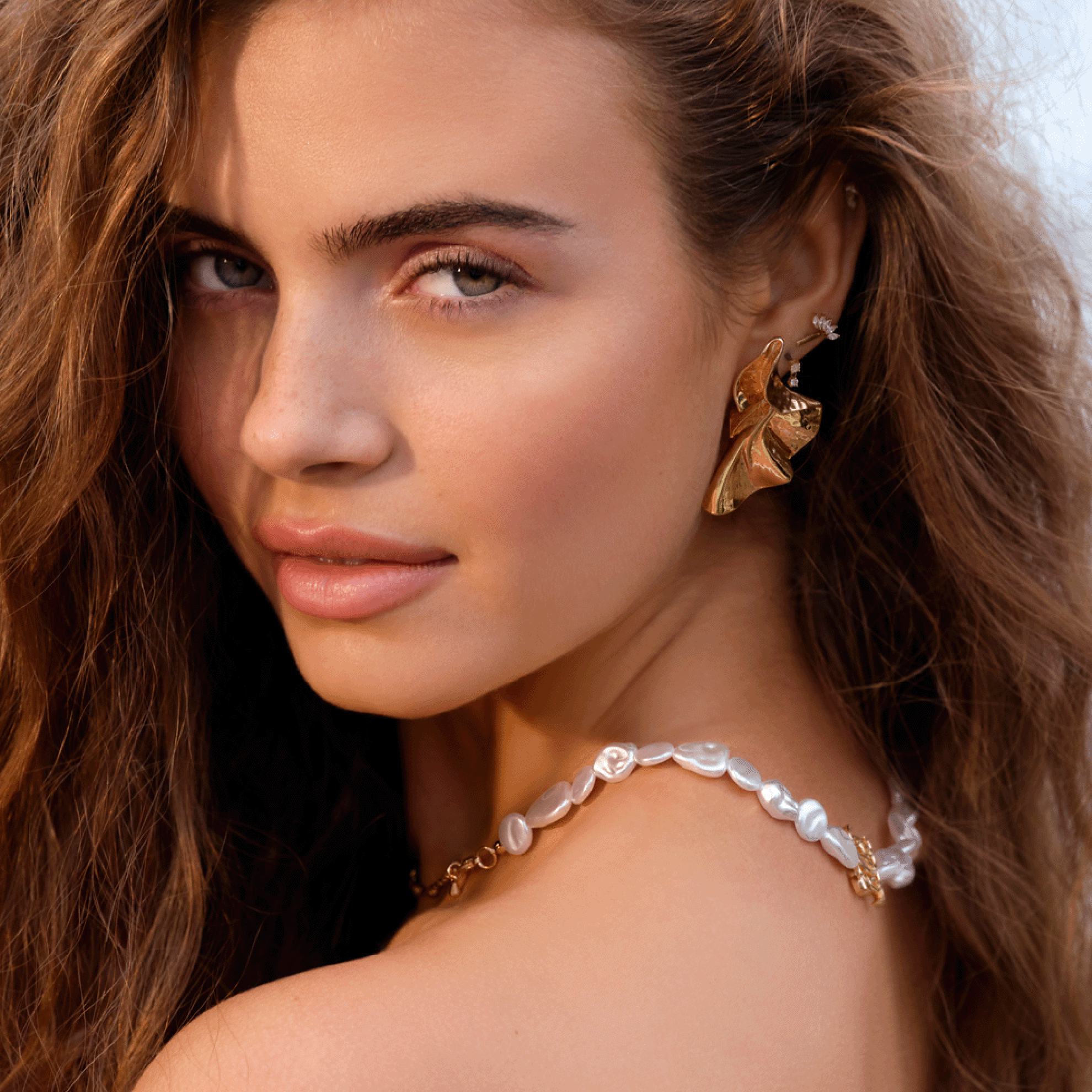 a woman with long brown hair and a gold necklace