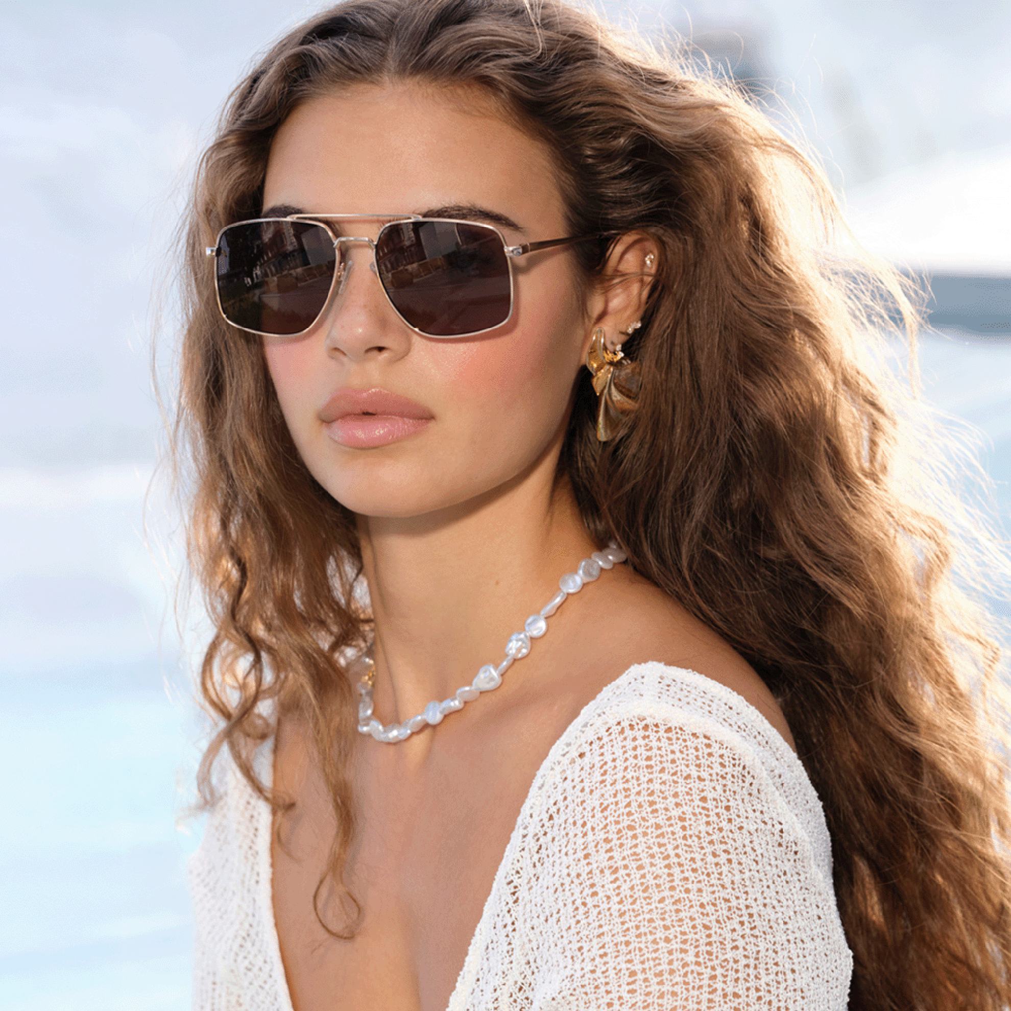 a woman wearing sunglasses and a white shirt