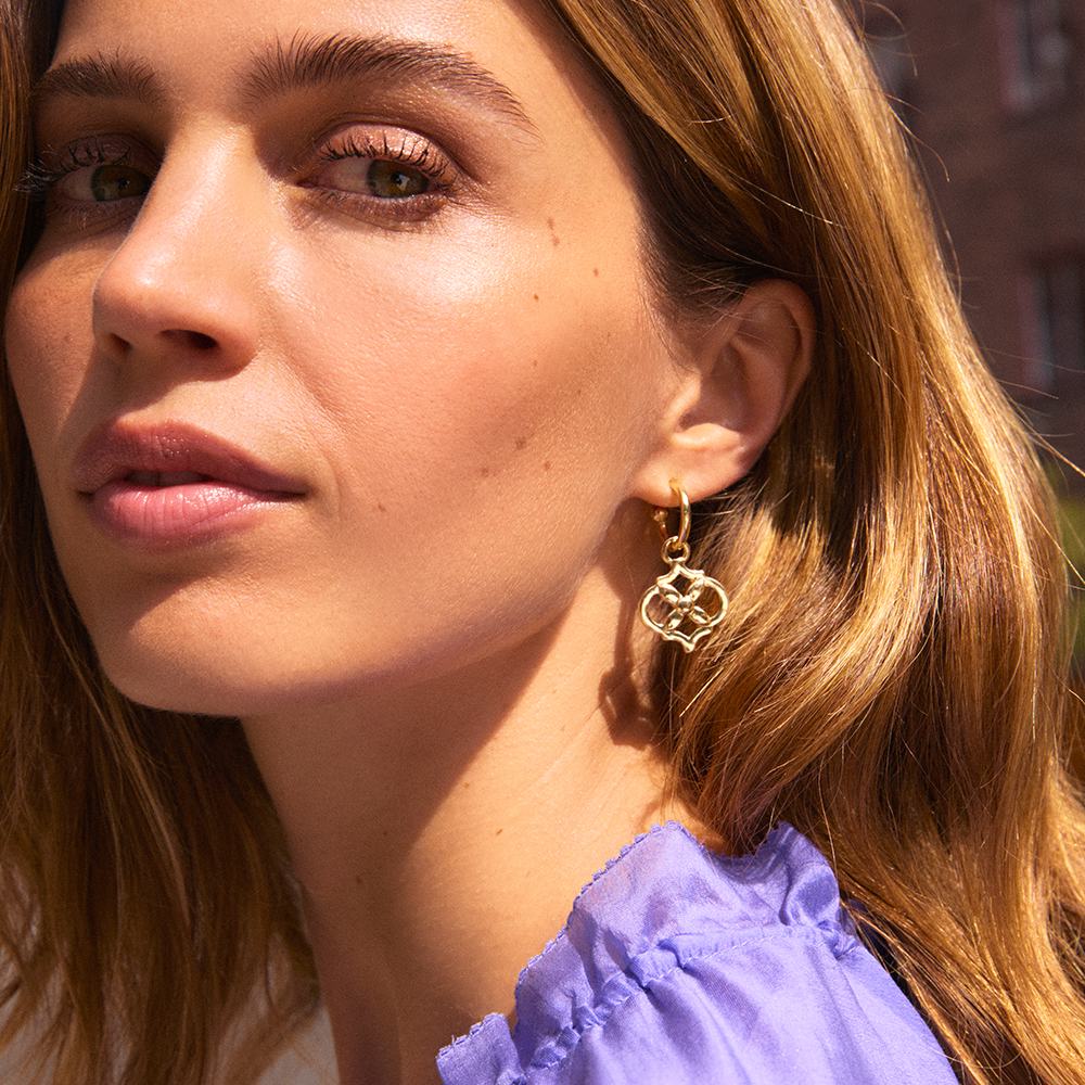 kobieta z długimi włosami, ubrana w fioletową koszulę i kolczyki