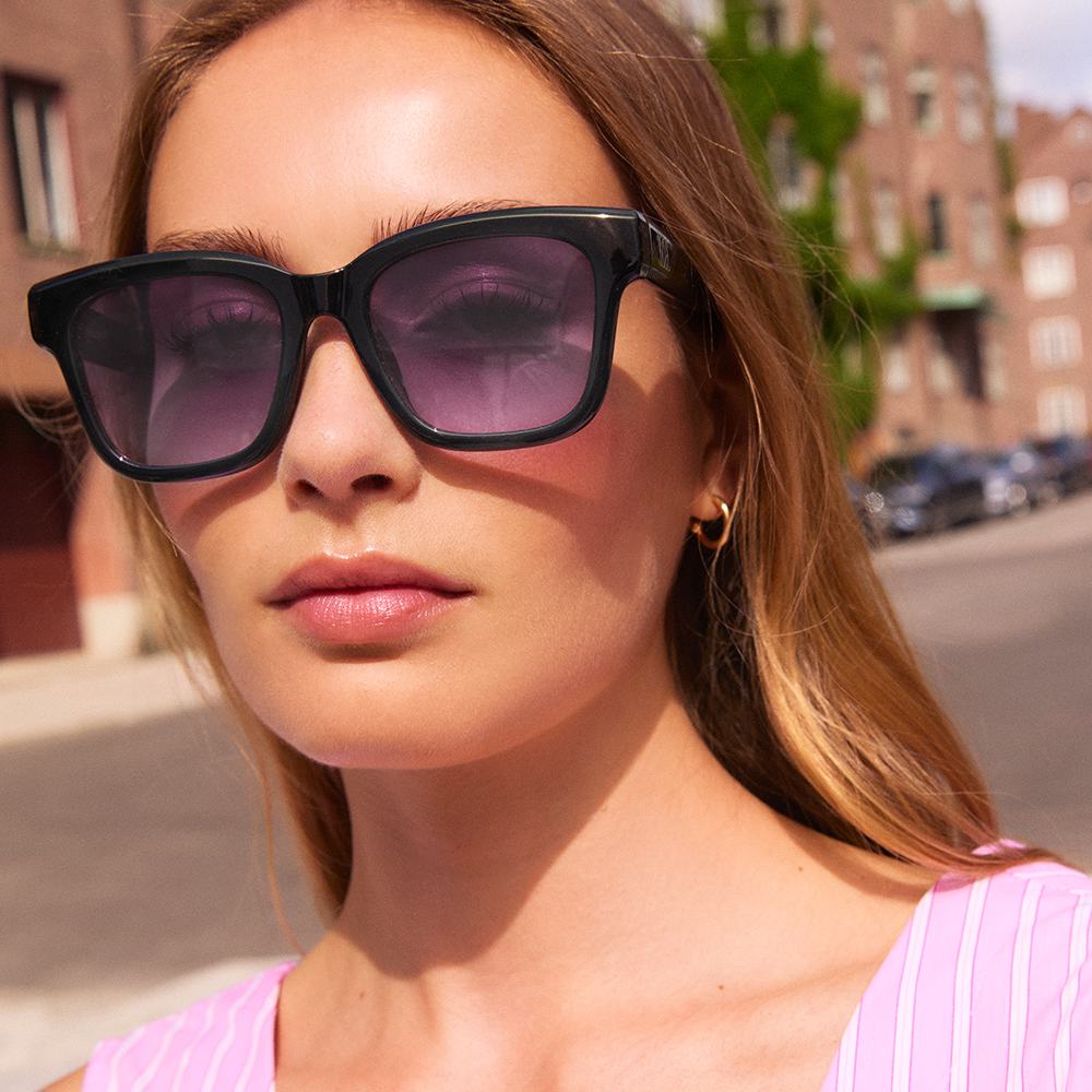 een vrouw met een zonnebril en een roze shirt