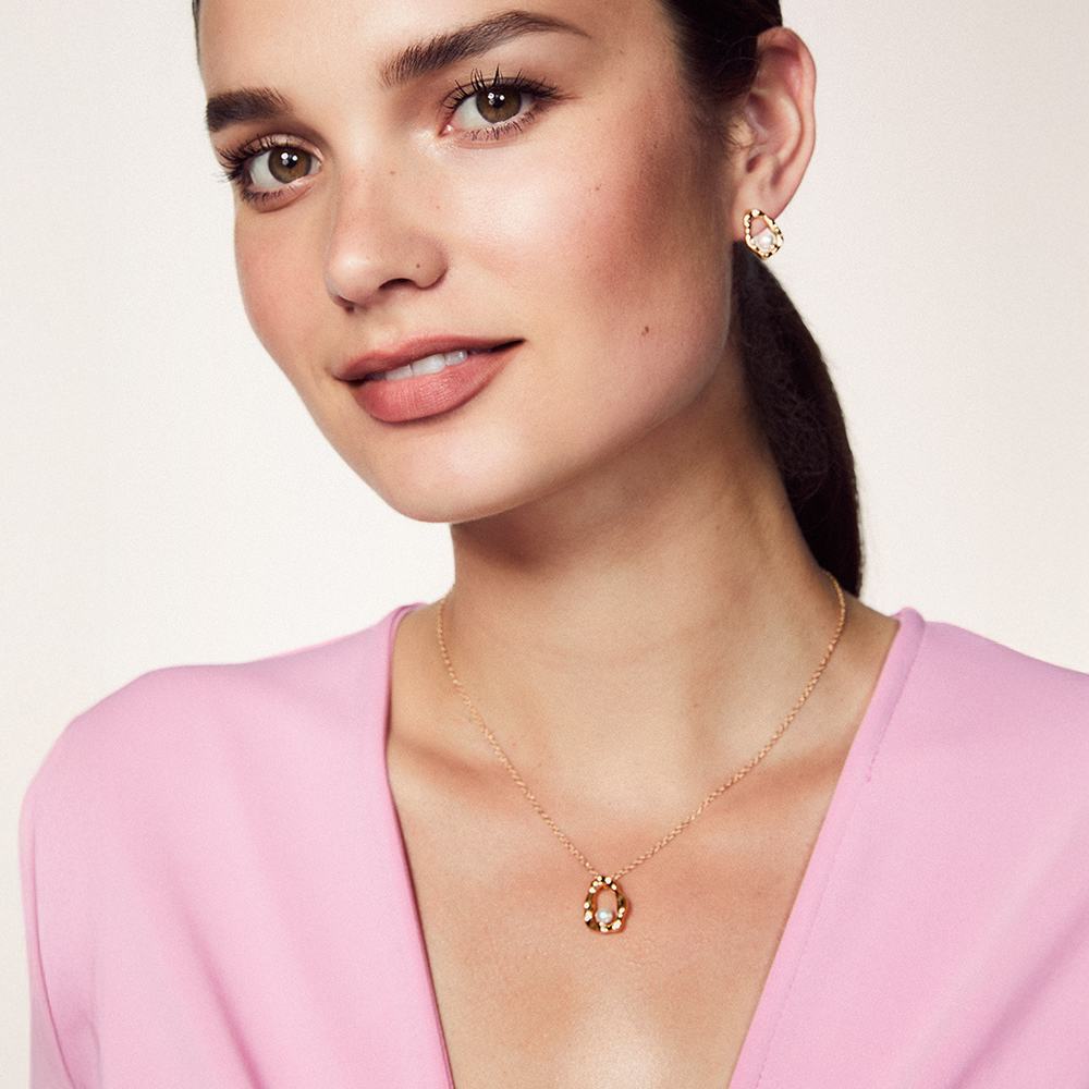 o femeie care poartă o cămașă roz și cercei