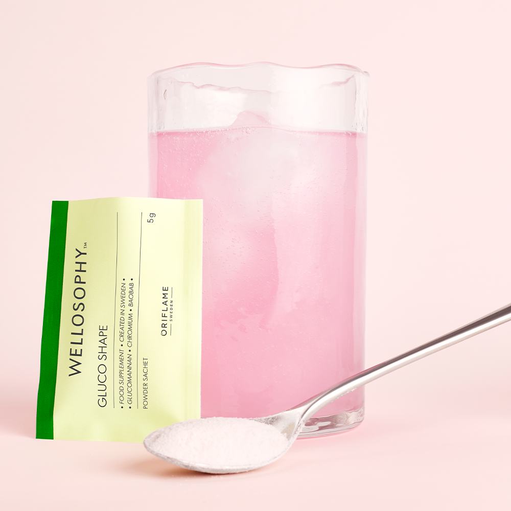 ένα ποτήρι υγρό με ένα κουτάλι και ένα πακέτο ζάχαρη